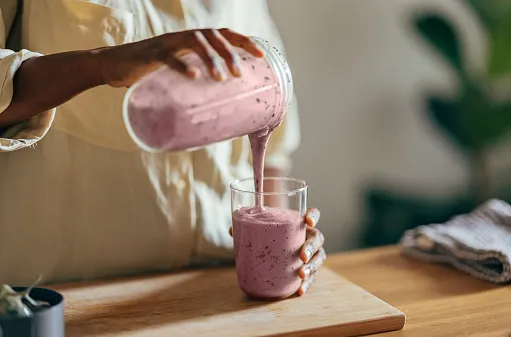 anonymous afro american woman pouring a smoothie into a glass