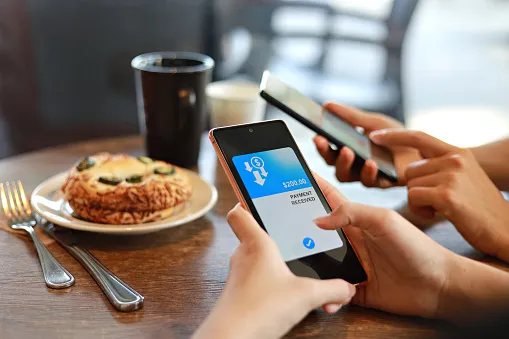 friends splitting bill sending and receiving payment of the meal through digital wallet