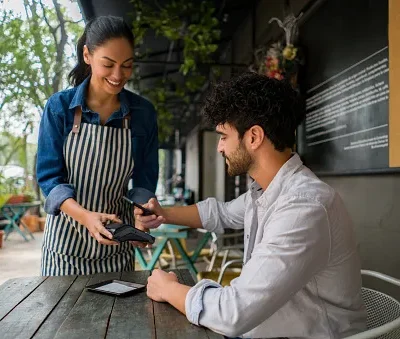 man making a contacless payment at a restaurant using his cell phone