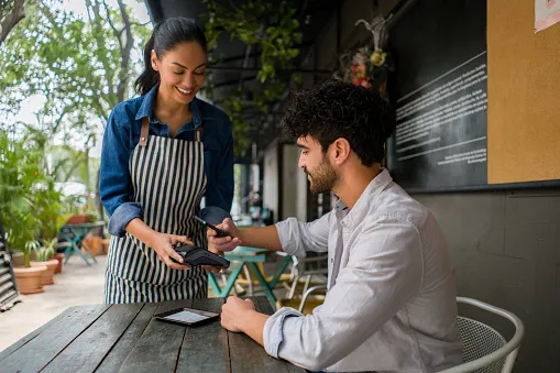 man making a contacless payment at a restaurant using his cell phone