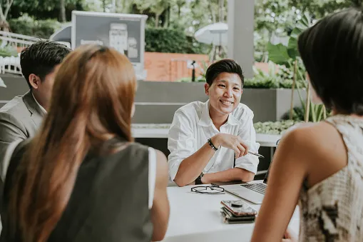 portrait of asian non binary gender officer while resting at cafe with colleague