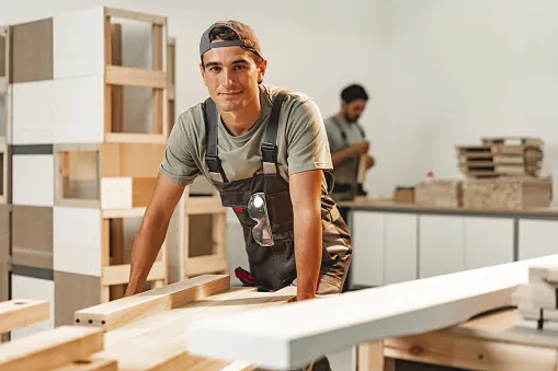 portrait of young male carpenter standing in the wood workshop