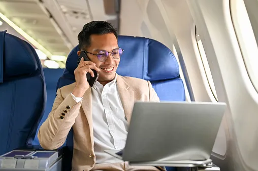 successful asian businessman looks at his laptop screen on the phone during the flight