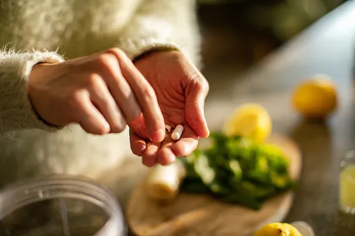 young woman taking a health supplement in the kitchen